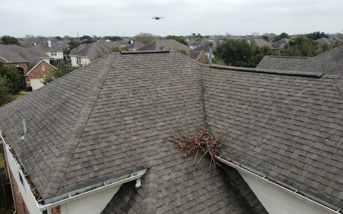 Aerial view of a shingle roof with valleys, gutters, and a drone in the distance