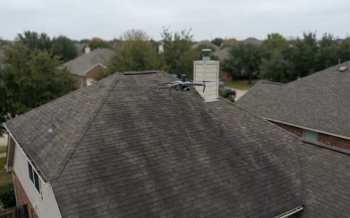 Quadcopter flying above a residential roof during an aerial inspection