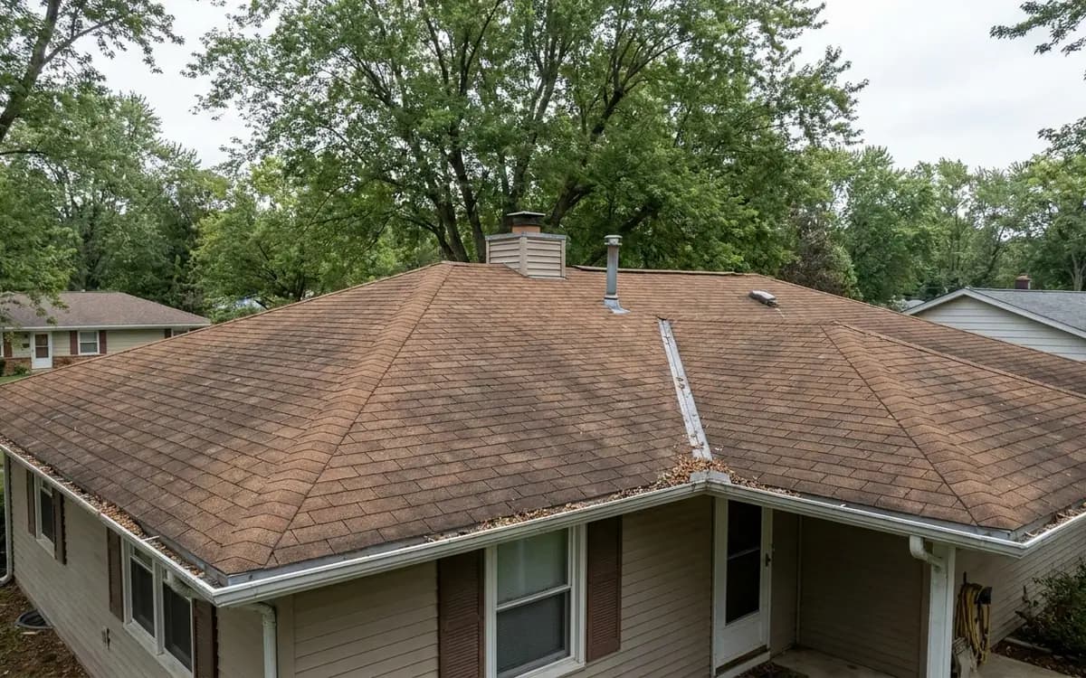 Wide view of a residential roof with flashing, gutters, and leaf debris